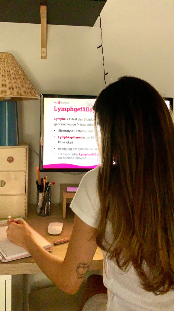 Eine Teilnehmerin des MedAT-Mentorings sitzt am Schreibtisch und lernt mit digitalen Lernunterlagen über das Lymphsystem. Auf dem Bildschirm sind strukturierte Inhalte aus dem MedAT-Vorbereitungskurs zu sehen.