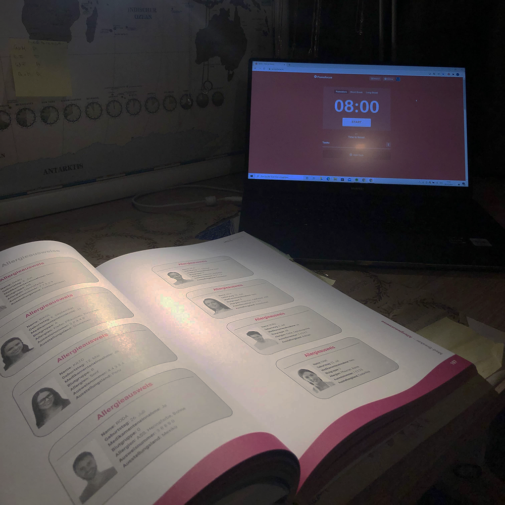 Lernumgebung für MedAT-Vorbereitung: Offenes Lehrbuch mit medizinischen Begriffen und Porträts, daneben Laptop mit Pomodoro-Timer – effizientes Lernen für Matura und MedAT-Test