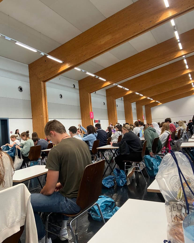 MedAT-Aufnahmetest für die Medizinischen Universität Innsbruck – Studieninteressierte sitzen am Testtag in einer Halle an Schreibtischen und bereiten sich auf den Test vor. Für das Medizinstudium Innsbruck muss man den MedAT bestehen.