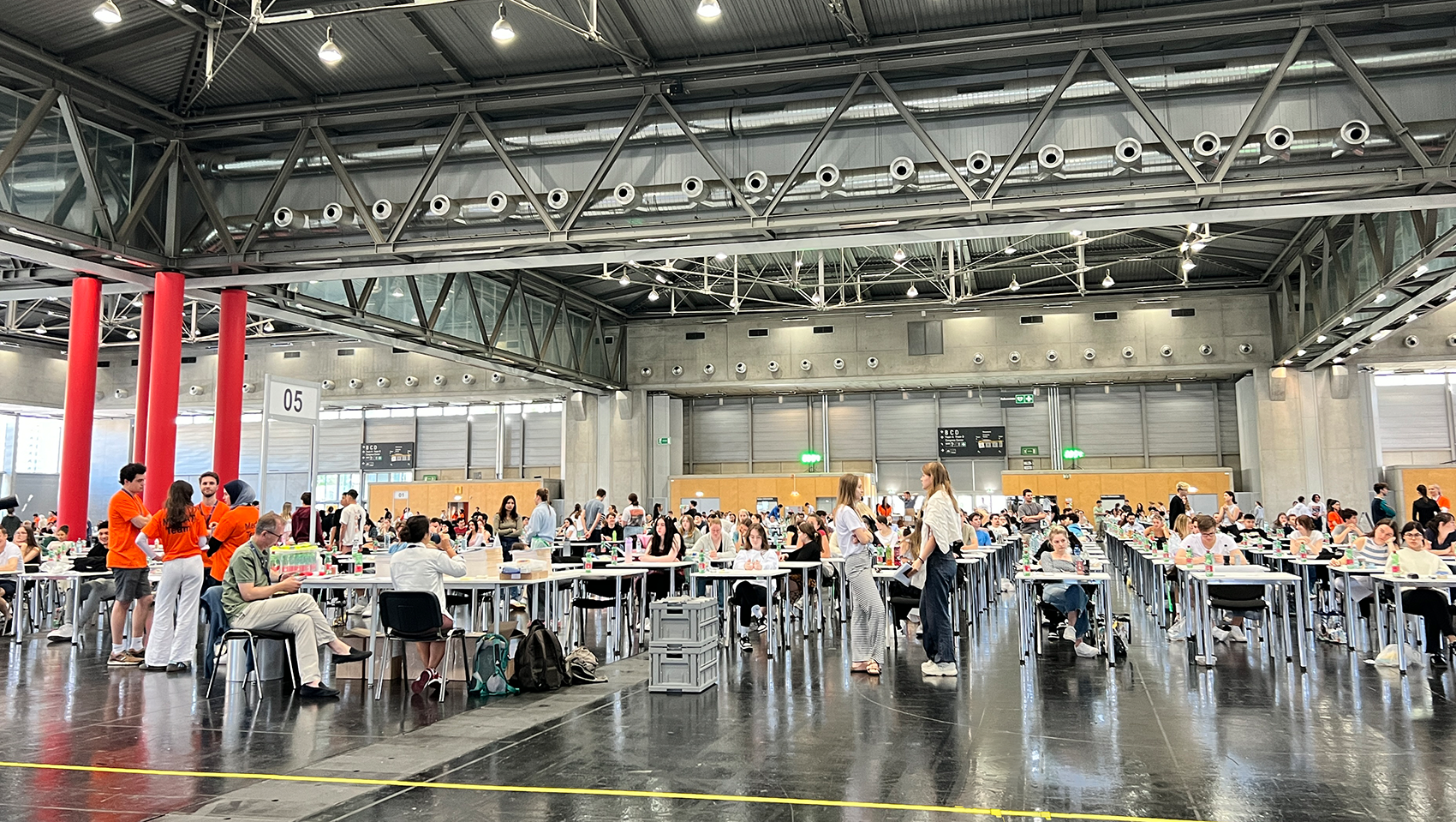 Das Bild zeigt den großen Veranstaltungssaal mit vielen Menschen, die an Tischen sitzen und sich auf den MedAT in Wien vorbereiten. Insgesamt herrscht eine lebhafte, aber konzentrierte Atmosphäre.